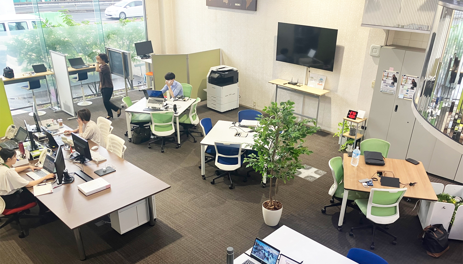 明るいオフィススペースで作業する人々。開放感のある環境でPC作業を行う様子